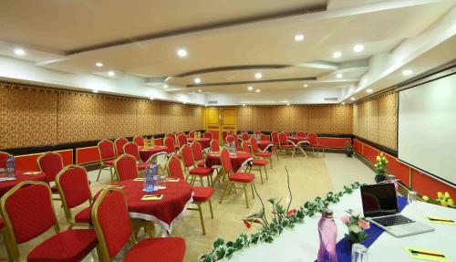 a conference room with red chairs and tables and a laptop at Royal Court in Madurai