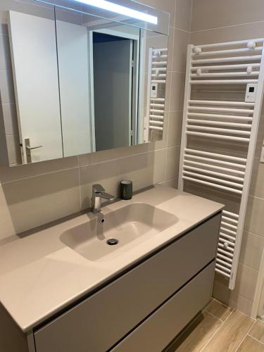 une salle de bain avec un lavabo et un miroir dans l'établissement Appartement 65m2 avec balcon vues partielles mer à 150m de la plage et centre, wifi et parking privé, à Blonville-sur-Mer