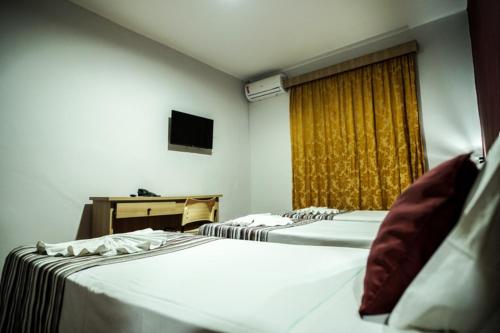 a hotel room with two beds and a window at Hotel Euro Suite Poços de Caldas By Nacional Inn in Poços de Caldas