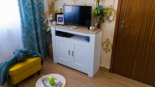 a living room with a television on a white cabinet at Casa Rodrigues in Santiago do Cacém