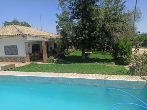 a house with a swimming pool in front of a house at Finca Rústica La Palmera in Utrera