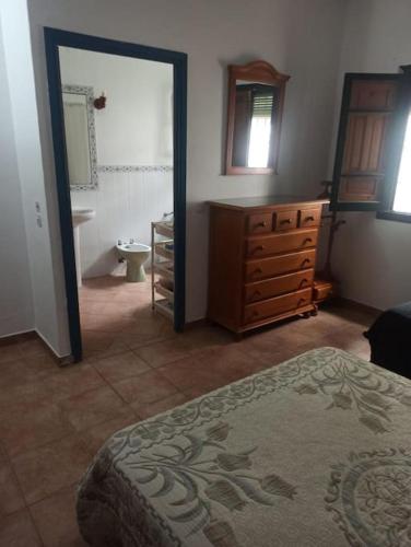 a bedroom with a bathroom with a sink and a dresser at Finca Rústica La Palmera in Utrera