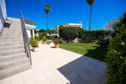 a walkway in a yard with stairs and palm trees at Villa Venera Fontane Bianche Charme Apartments in Fontane Bianche