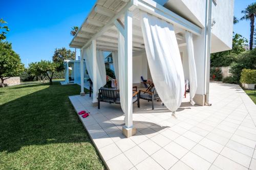 a patio with white curtains on a house at Villa Venera Fontane Bianche Charme Apartments in Fontane Bianche