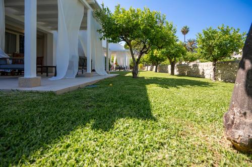 a house with a yard with grass and trees at Villa Venera Fontane Bianche Charme Apartments in Fontane Bianche