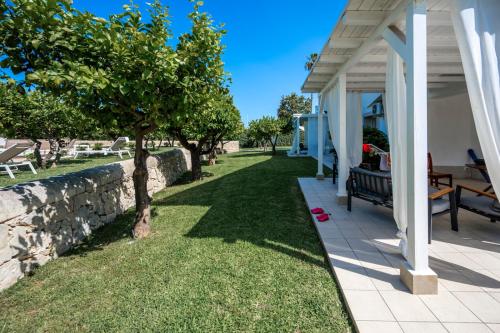a white house with a yard with a stone wall at Villa Venera Fontane Bianche Charme Apartments in Fontane Bianche