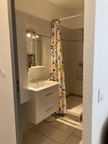 une salle de bain blanche avec un lavabo et une douche dans l'établissement Appartement T2 lumineux et moderne avec parking - 4VOIL245 -, à Canet