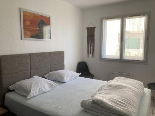 un lit avec deux oreillers dessus dans une chambre dans l'établissement Appartement T2 lumineux et moderne avec parking - 4VOIL245 -, à Canet