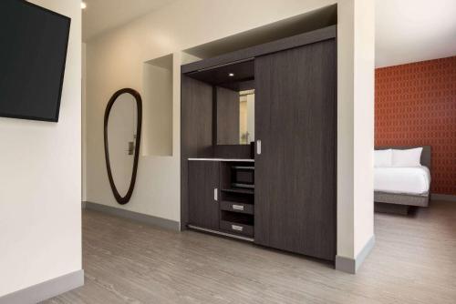 a bedroom with a large cabinet with a mirror at The Orbit Hotel, Trademark Collection by Wyndham in Fairview Park