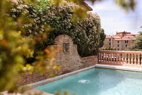 a swimming pool with a brick fence and flowers at Hotel Vannucci in Città della Pieve