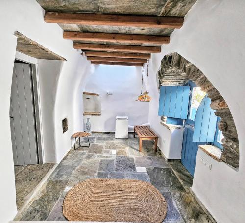 a room with a stone floor and a ceiling with blue doors at Tinoshomelidays Residences in Venardatos