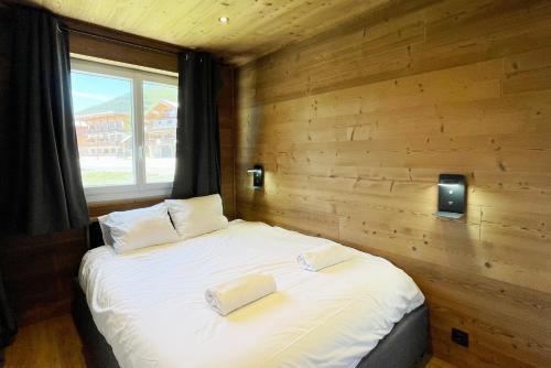 un lit dans une chambre avec un mur en bois dans l'établissement Homency - Résidence Azur A1, à L'Alpe-d'Huez