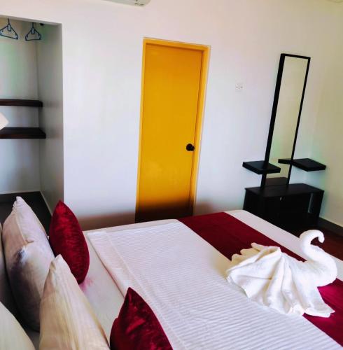 a bedroom with a bed with red pillows and a yellow door at French garden Pragash Beach Hotel in Trincomalee