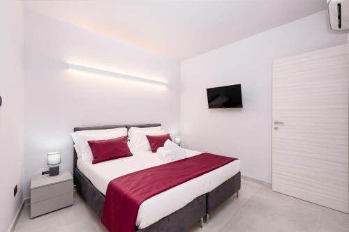 a white bedroom with a large bed with red pillows at La Grignola Apartments in Canale