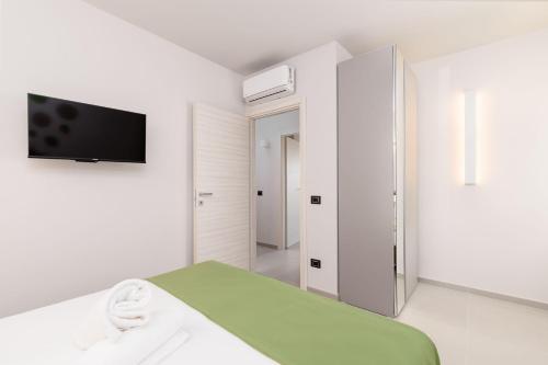 a white room with a bed and a flat screen tv at La Grignola Apartments in Canale
