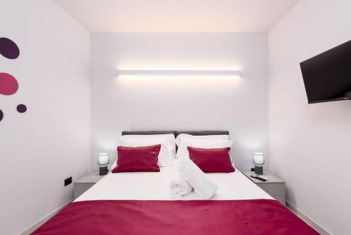a bedroom with a bed with red and white pillows at La Grignola Apartments in Canale