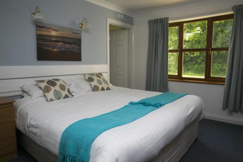 a bedroom with a bed with a blue blanket on it at Trethorne Hotel & Golf Club in Launceston