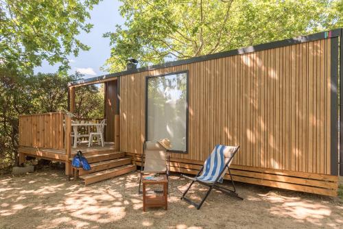 a tiny house with a deck and two chairs at Camping La Plage Argelès in Argelès-sur-Mer