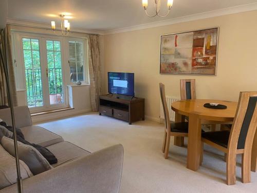 a living room with a table and a television at Haven With Patio in Basingstoke