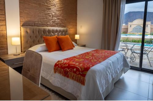 a bedroom with a bed with orange pillows and a window at Luna de Cafayate Hotel Boutique in Cafayate