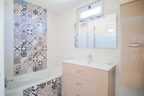 une salle de bain avec un lavabo, une baignoire et un miroir dans l'établissement -Mave Mai- Magnifique T3 surplombant la mer, à Concarneau