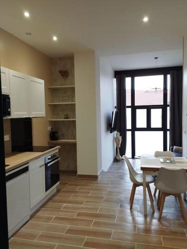 une cuisine avec des armoires blanches et une table et une salle à manger dans l'établissement Rez de chaussée Gambetta, à Roanne