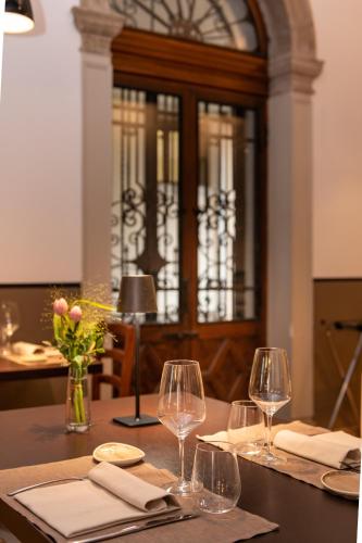 a dining table with wine glasses and a cabinet at Hotel Casa Del Pellegrino in Padova