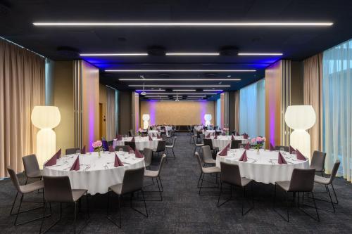 a banquet hall with white tables and chairs and a screen at Mercure Debrecen in Debrecen