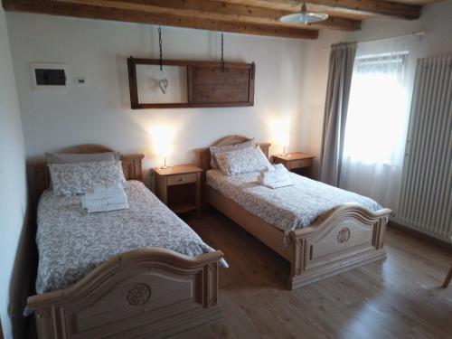 a bedroom with two beds and a window at Agriturismo La Casa Nei Boschi in Colderù