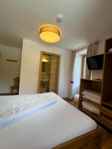 a bedroom with a white bed and a television at Bar-Restaurant-Pizzeria Antermont B&B in Carezza al Lago