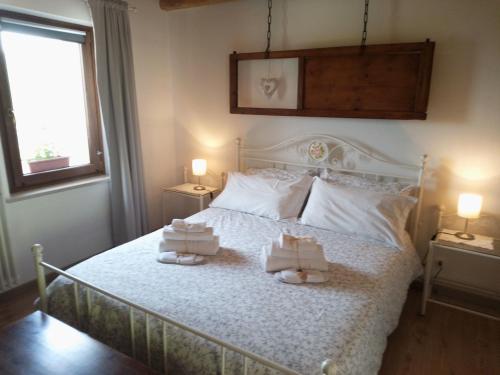 a bedroom with a white bed with towels on it at Agriturismo La Casa Nei Boschi in Colderù
