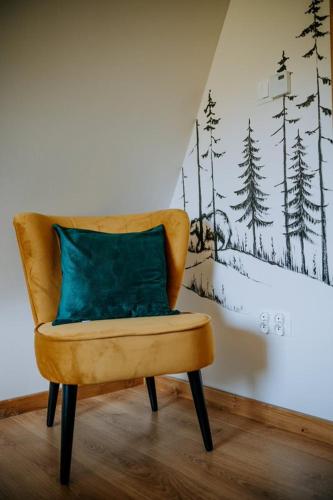 a yellow chair with a blue pillow in a room at Domek z kominkiem i sauną w górach - Domek Pod Jeziorem in Murzasichle