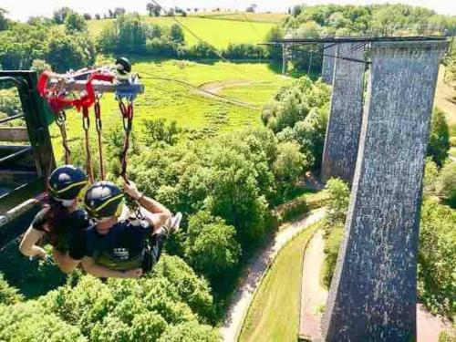 two people riding on a zip line in the air at Spacious Luxury countryside retreat in Estry