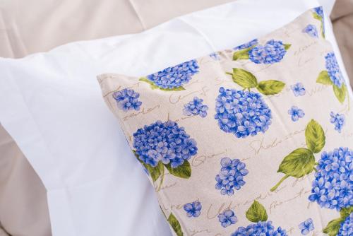 a pillow with blue flowers on a white dress at Casa da Praça Double room - by Casas na Ilha in Funchal