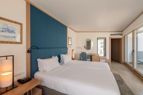 a bedroom with a large bed and a blue wall at Sesimbra Oceanfront Hotel - Preferred Hotels and Resorts in Sesimbra