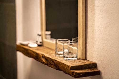 two glasses sitting on a wooden shelf in front of a mirror at Casa Veche Leheceni in Apuseni in Leheceni