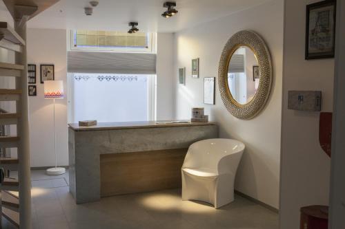 baño con espejo y silla blanca en Stadslogement Kingsize en Sneek