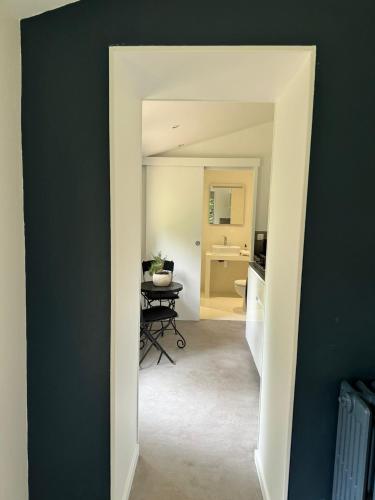 a hallway with a room with a table in it at Grand studio neuf sur jardin privé a 35 mn du RER A Charles de Gaulle Etoile in Maisons-Laffitte