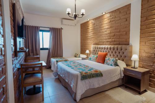 a bedroom with two beds and a brick wall at Luna de Cafayate Hotel Boutique in Cafayate