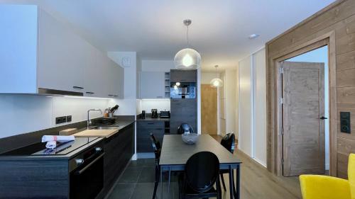 eine Küche mit einem Tisch und einigen Stühlen in der Unterkunft Homency - Résidence Fermes de l'Alpe A003 in L'Alpe-d'Huez