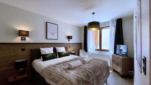 ein Schlafzimmer mit einem großen Bett und einem Fernseher in der Unterkunft Homency - Résidence Fermes de l'Alpe A003 in L'Alpe-d'Huez
