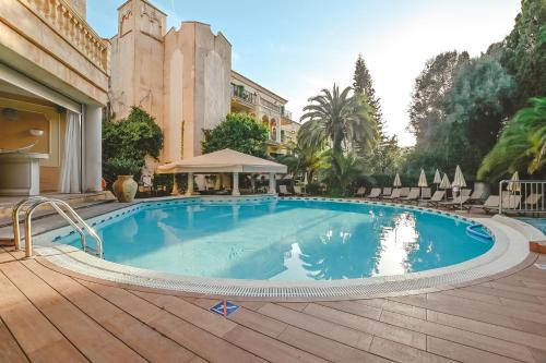 a large swimming pool with a wooden deck next to a building at Lago Garden Apart-Suites & Spa Hotel in Cala Ratjada
