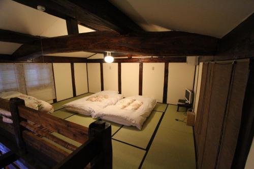 a room with two beds and a bench in it at Minshuku Takizawa in Takayama