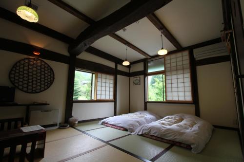 a bedroom with two beds in a room with windows at Minshuku Takizawa in Takayama
