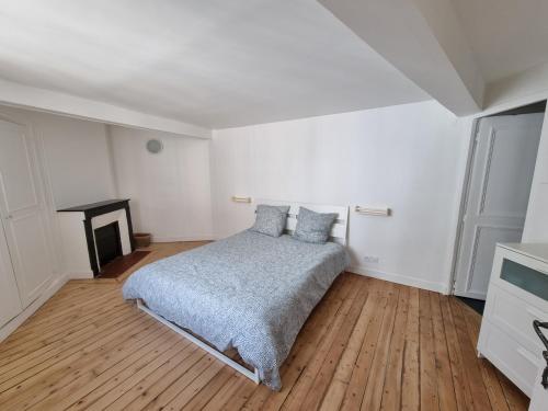 une chambre blanche avec un lit et une cheminée dans l'établissement Beau 4 pièces au cœur de Paris, à Paris