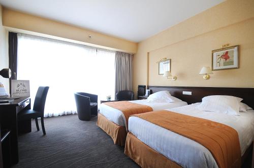 a hotel room with two beds and a desk at Splendid Hotel & Spa Nice in Nice
