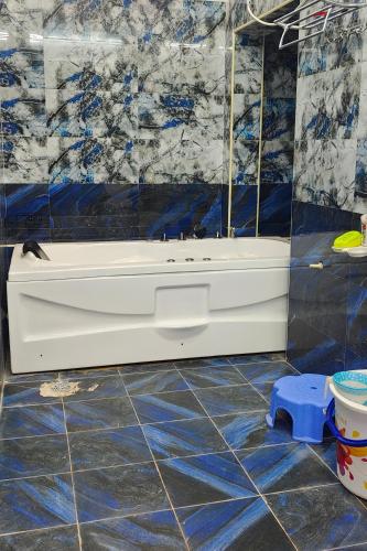 a bathroom with a tub and blue and white tiles at JK Palace in Yelagiri