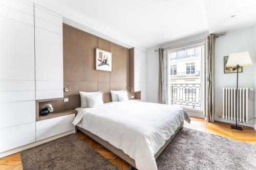 une chambre avec un grand lit et une grande fenêtre dans l'établissement Luxury Living Georges V, à Paris