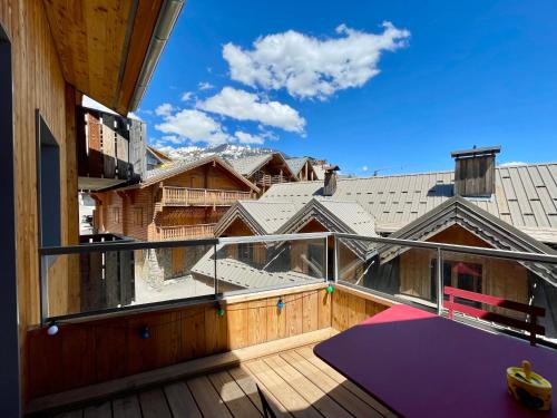 un balcon avec un tapis violet sur une terrasse en bois dans l'établissement Homency - Résidence Fermes de l'Alpe A302, à L'Alpe-d'Huez