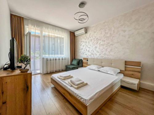 a bedroom with a bed and a chair and a television at Апартамент Tiana in Tsarevo